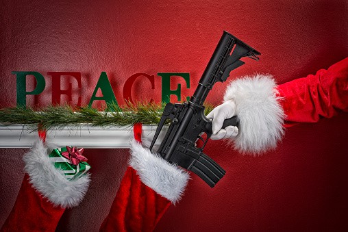 A grtty image of Santa's hand placing an assault rifle into a Christmas Stockings hanging from a white mantel shelf on a red wall with pine garland and a "PEACE" sign ~ gifts for gun lovers