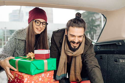 Young couple packing Christmas gifts into the car trunk after shopping. | 21 Travel Gifts for Men
