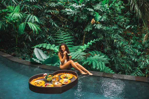 Girl relaxing and eating floating breakfast in jungle pool on luxury villa in Bali. Valentines day or honeymoon surprise. Tropical travel lifestyle. Black rattan tray in heart shape. ~pool gifts for mom