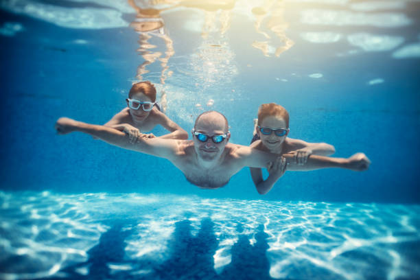 Father and sons playing underwater in resort pool. Family is playing underwater superheroes. Nikon D850 _pool gifts for dad