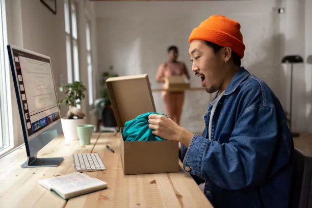 Cool looking Chinese man thrilled to open his online order at his modern apartment - gifts for couples moving in together